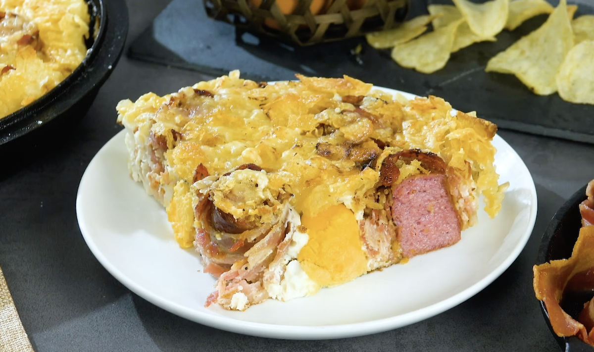 Eine Portion XXL-Omelett mit Bacon, Krakauer Würstchen und Chips auf einem Teller.