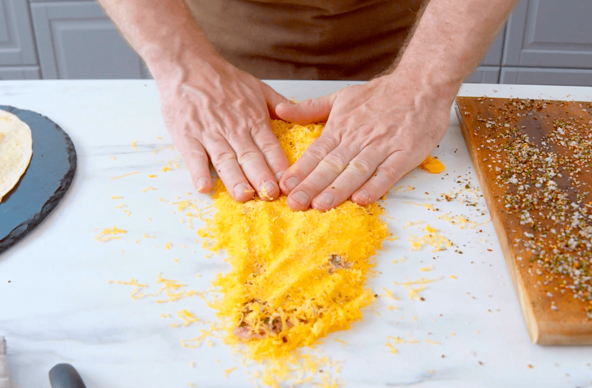 Ein Schweineschnitzel wird in geriebenem Cheddar paniert