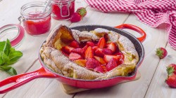 Riesiger Ofen-Pfannkuchen mit frischen Erdbeeren in roter Pfanne:
