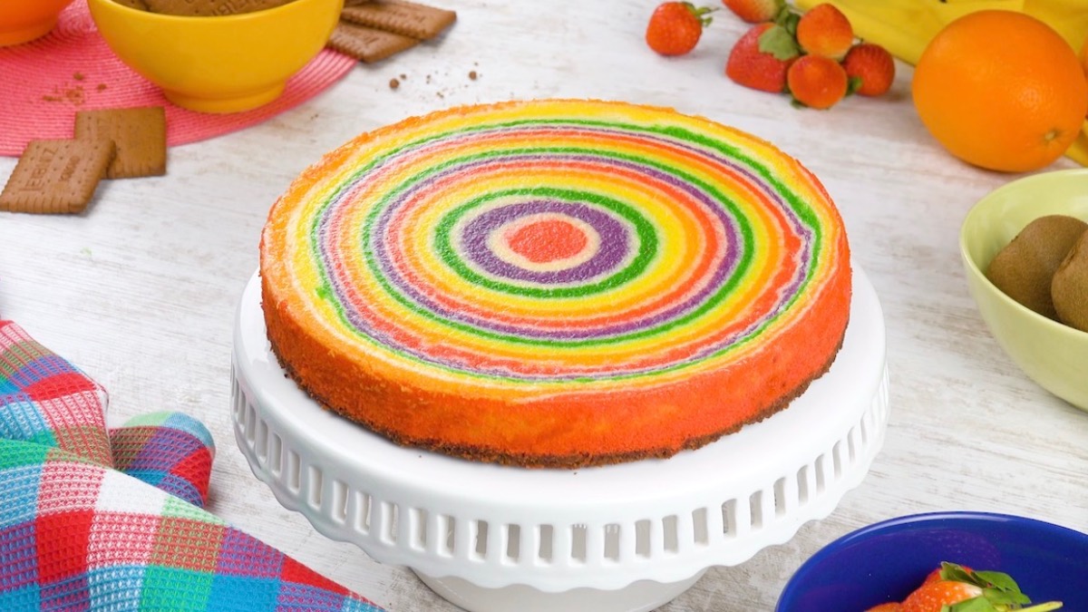 Ein Regenbogen-Fruchtkuchen auf einer Kuchenplatte.