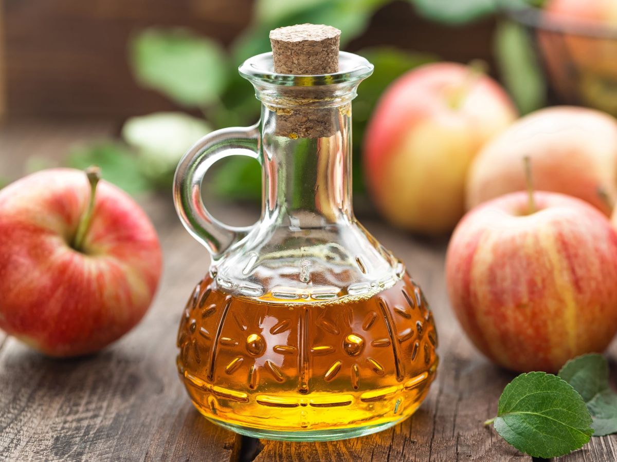 Bratapfel-LikÃ¶r in einer bauchigen Flasche, im Hintergrund liegen Ã„pfel.