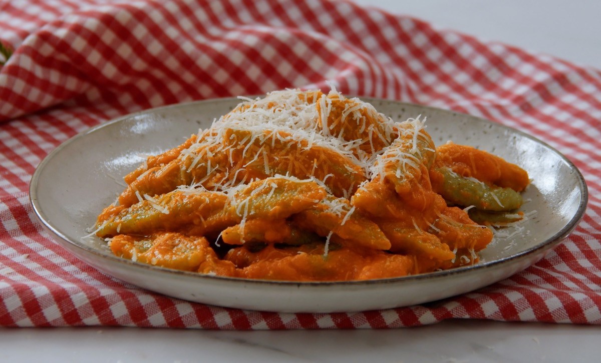 Eine Portion Brokkoli-Schupfnudeln mit geriebenem Parmesan auf einem Teller.