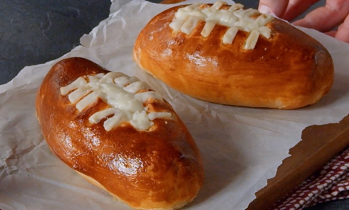 Zwei Football-Snacks mit Käsefüllung auf Backpapier.