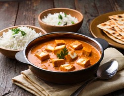 Tisch mit einer Schale Tofu Makhani, einer Schale Reis und Fladenbrot