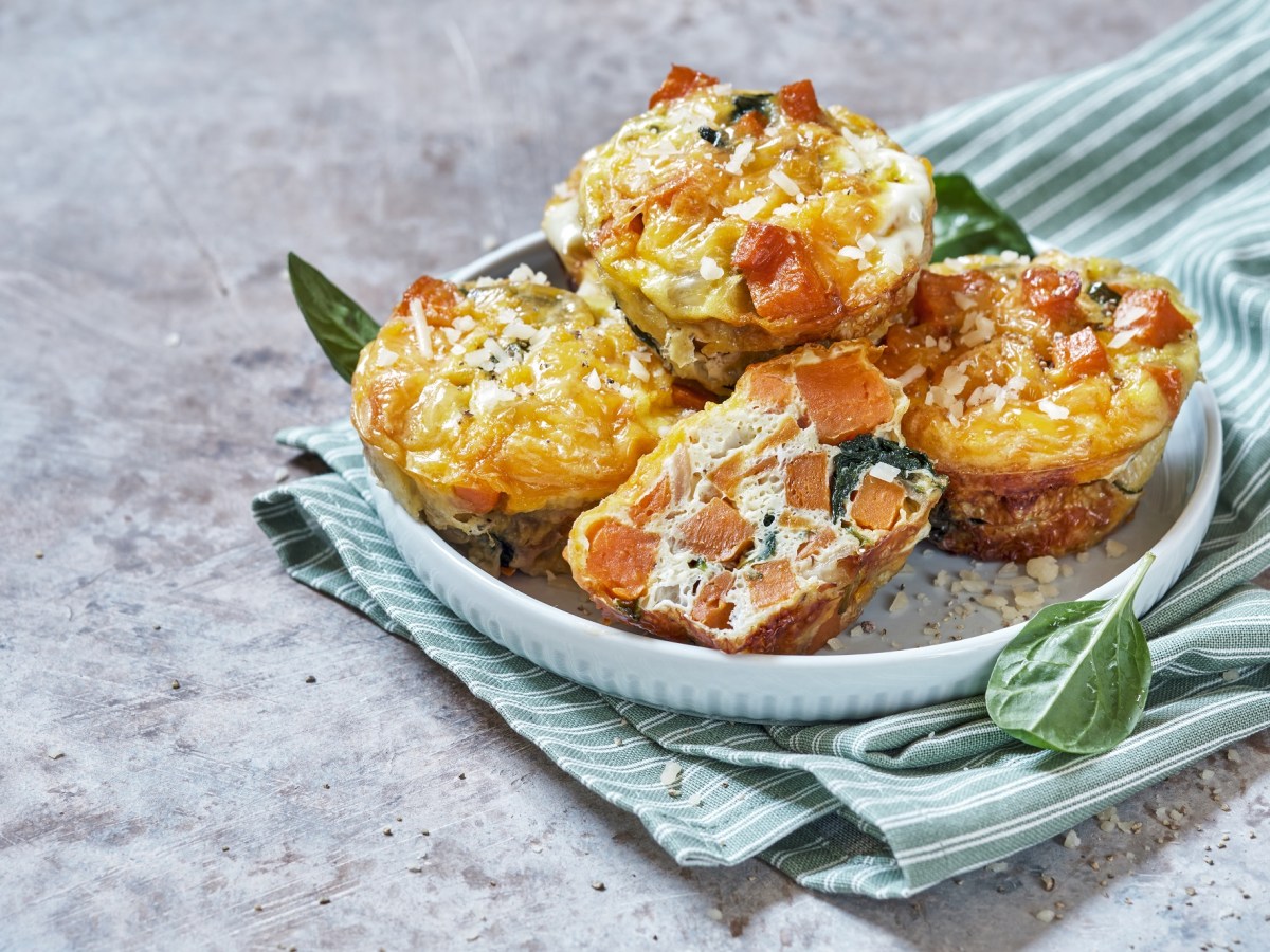 4 Kroketten-Muffins mit Gemüse und Schmand auf einem Teller, der auf einem gestreiften Geschirrtuch steht.