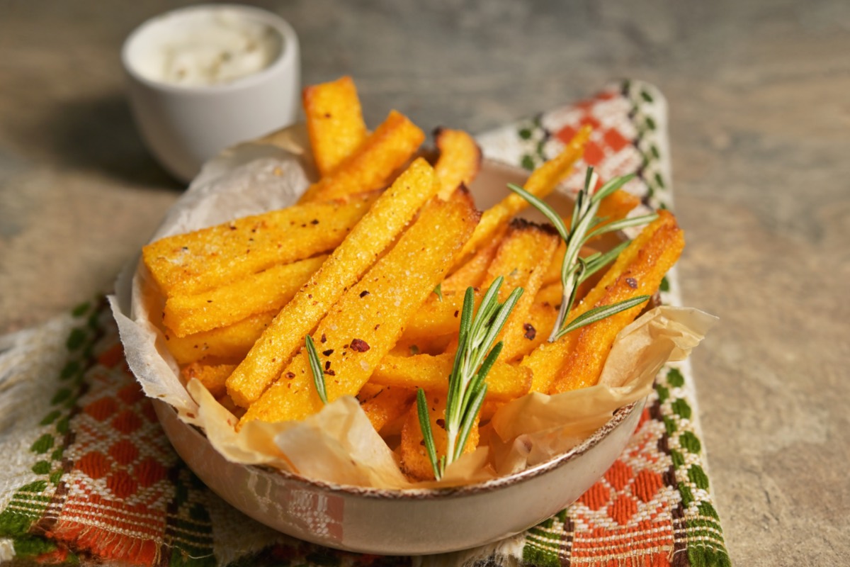 Polenta-Pommes in einer SchÃ¼ssel. Daneben steht ein SchÃ¤lchen mit Dip.