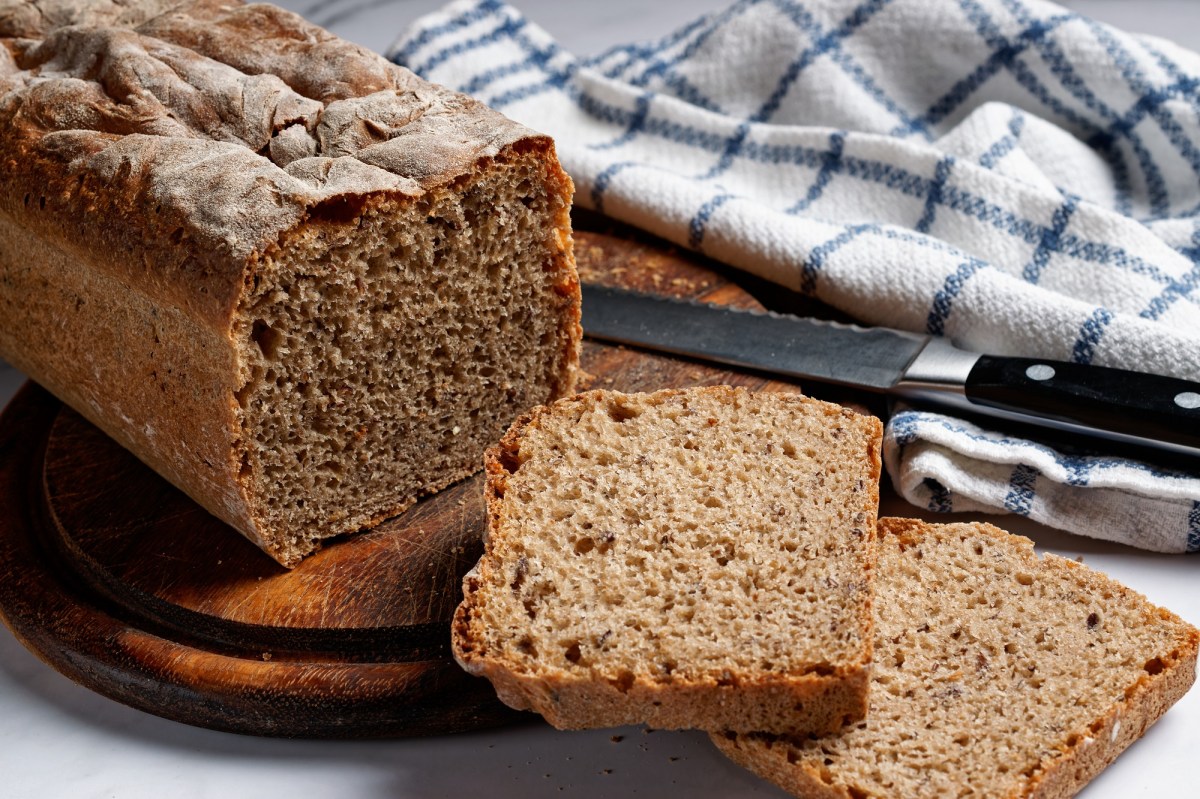 Brot backen ohne Hefe: ein angeschnittenes Kastenbrot, daneben ein kariertes Geschirrtuch.