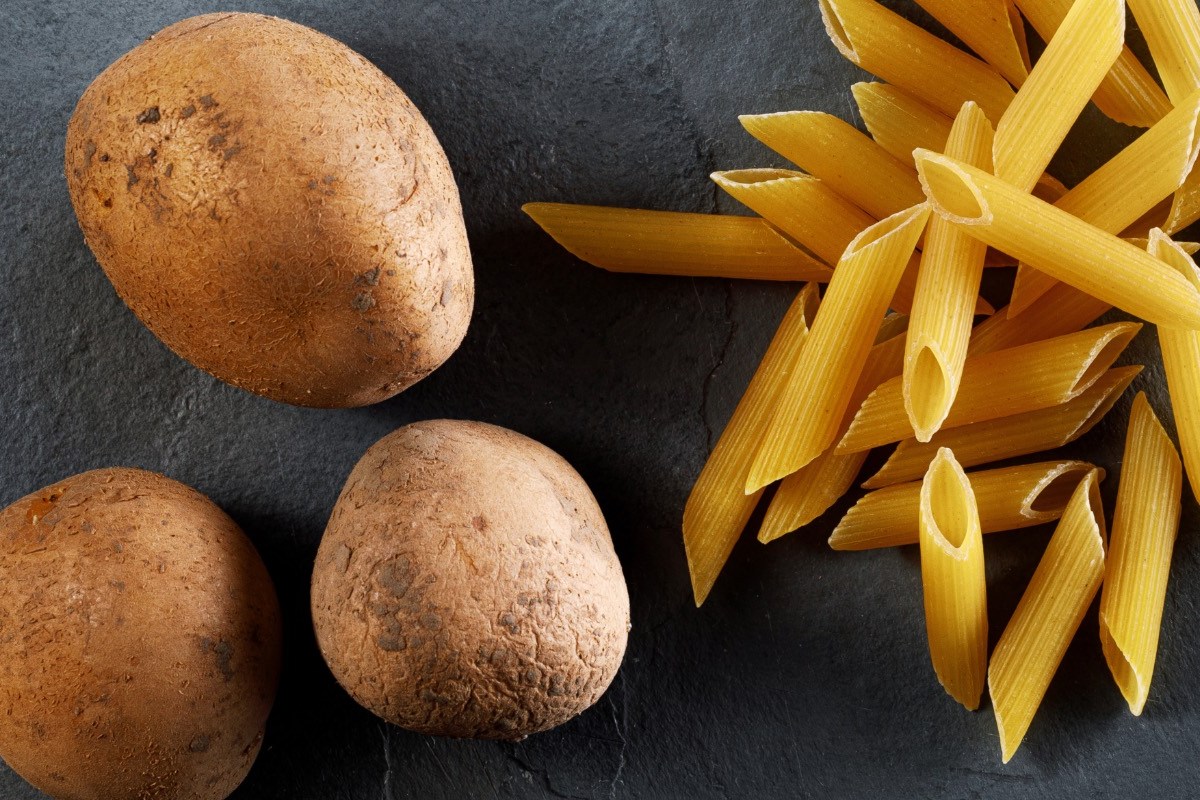 Was ist gesünder, Kartoffeln oder Nudeln: rohe Nudeln liegen neben rohen Kartoffeln.