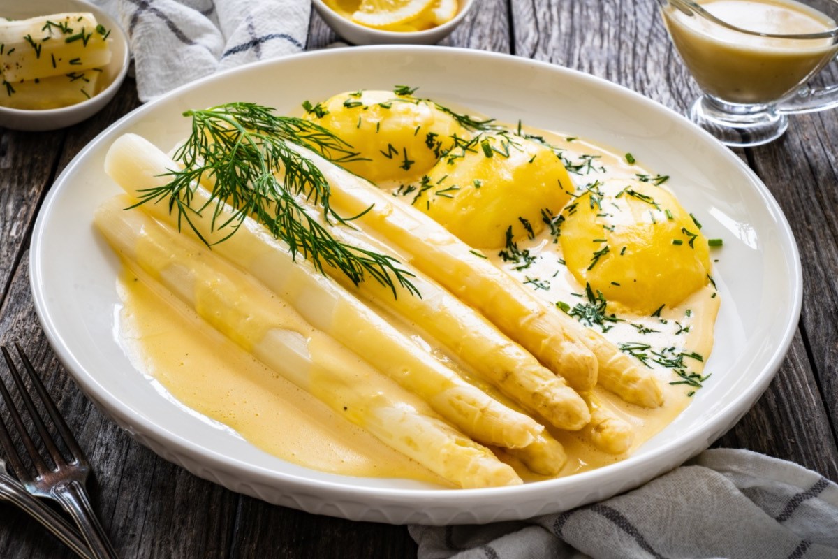 Wie viel Spargel pro Person: eine Portion Spargel mit Sauce hollandaise und Kartoffeln auf einem Teller.