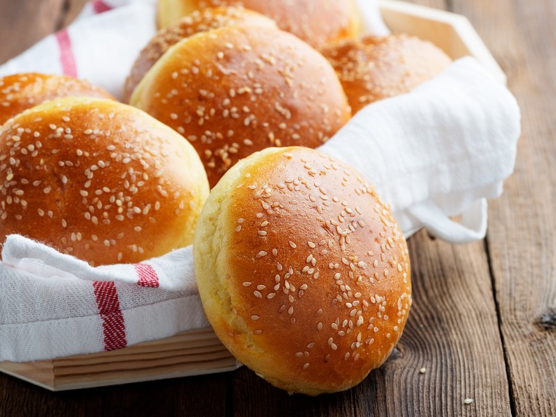 Burgerbrötchen selber machen: Mehrere selbstgemachte Burgerbrötchen in einem Korb, der mit einem Tuch ausgeschlagen ist.