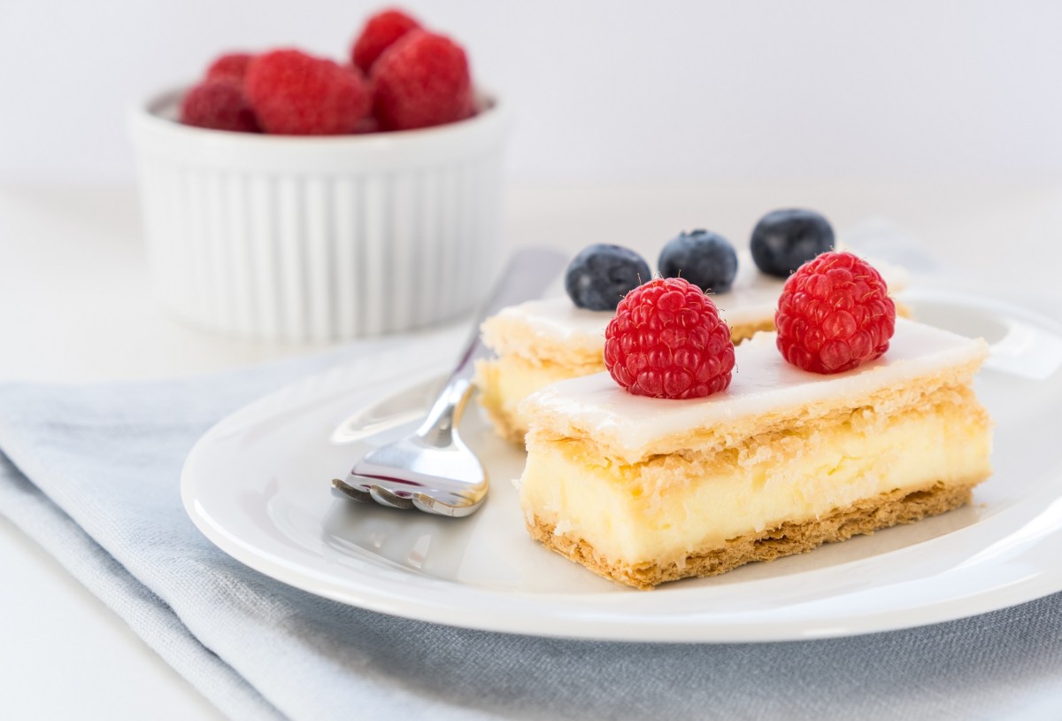 Cremeschnitte mit Beeren dekoriert.