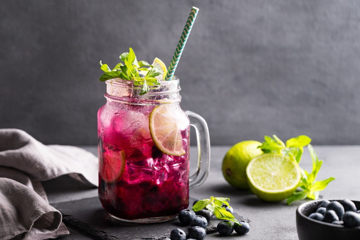 Ein Glas Heidelbeer-Mojito mit frischer Minze und Limetten.