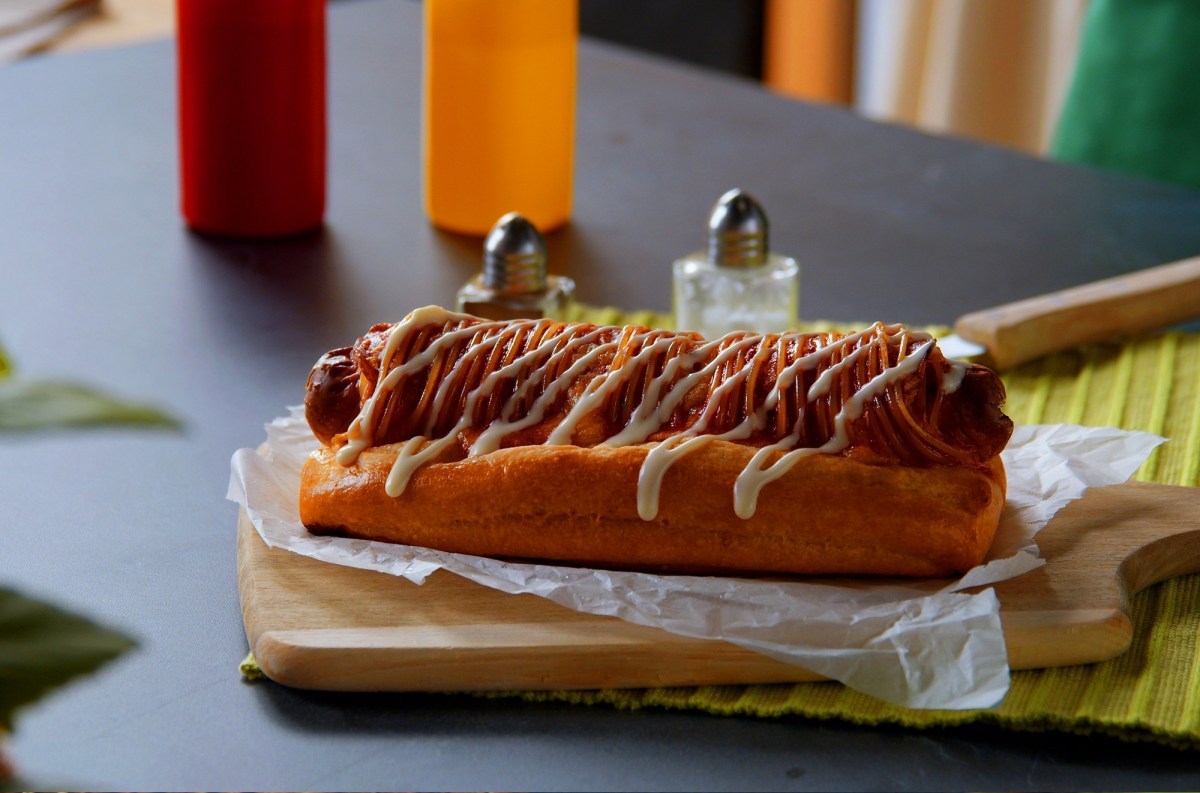 Pizza-Hot-Dog mit Mayonnaise auf einem Brett.