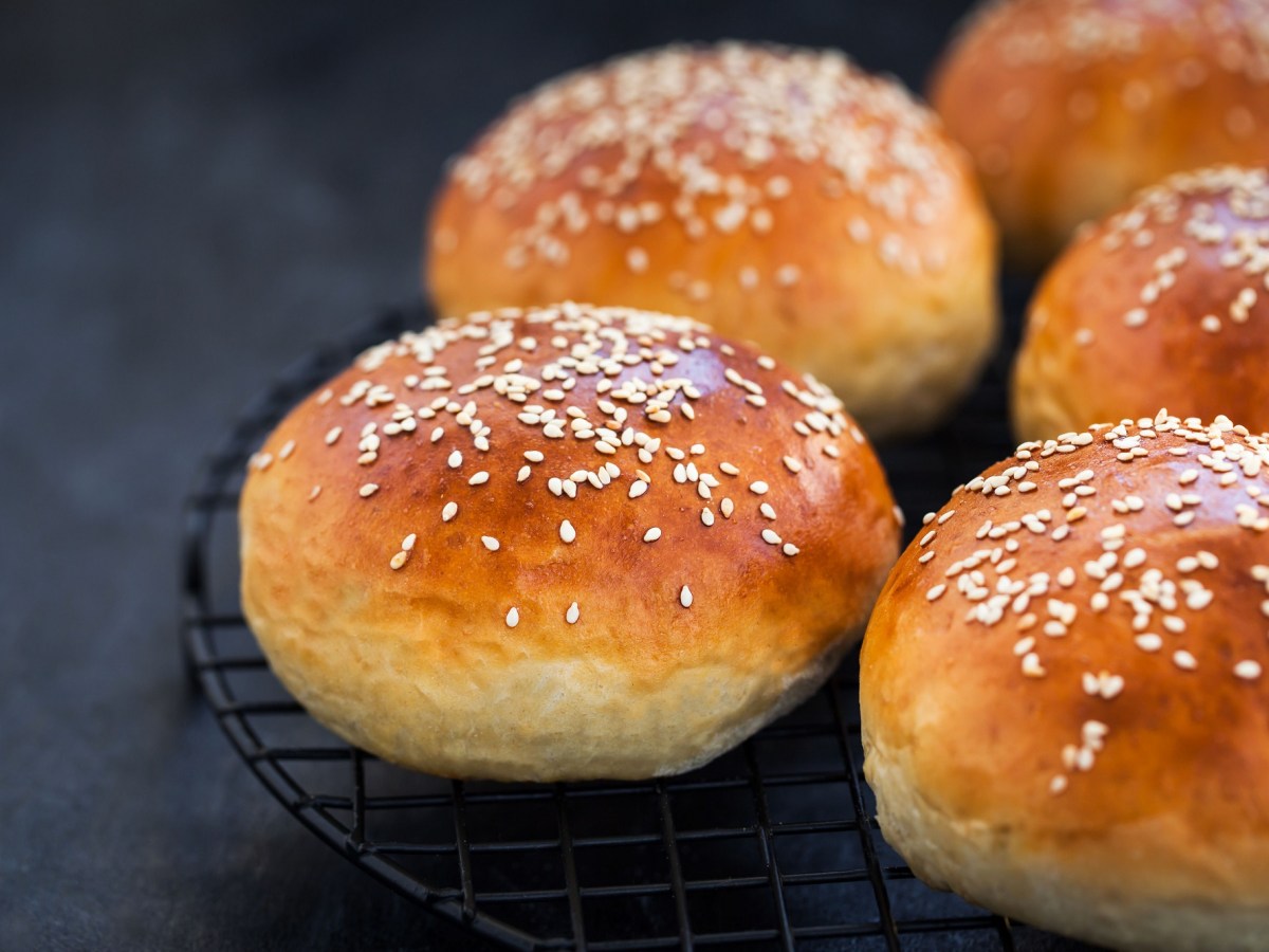 mehrere Joghurtbrötchen auf einem Gitter, mit Sesam bestreut.