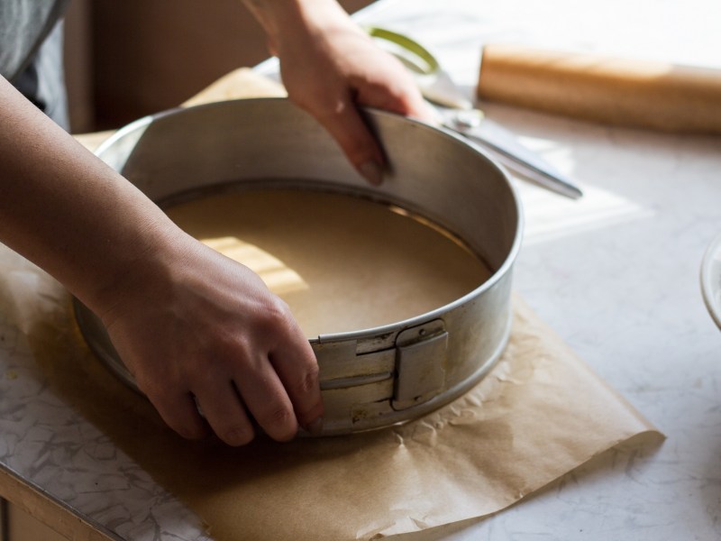 Eine Frau ist dabei, eine Kuchenform mit Backpapier auszulegen.