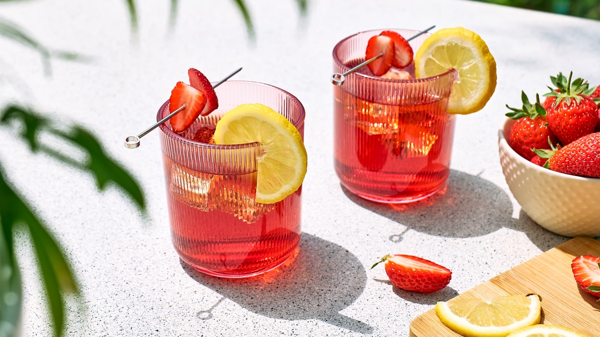 Zwei Gläser mit rosa Cocktail, Erdbeeren und Zitrone.
