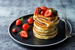 Ein Stapel Pancakes mit Schokoladenfüllung und Erdbeeren.