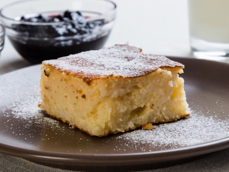 Ein Stück Reiskuchen, im Hintergrund ein Schälchen Fruchtkompott.