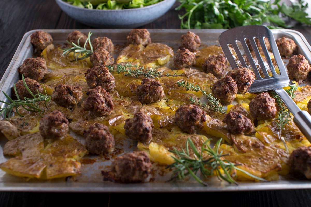 Ein Backblech mit Smashed Potatoes mit Bouletten.