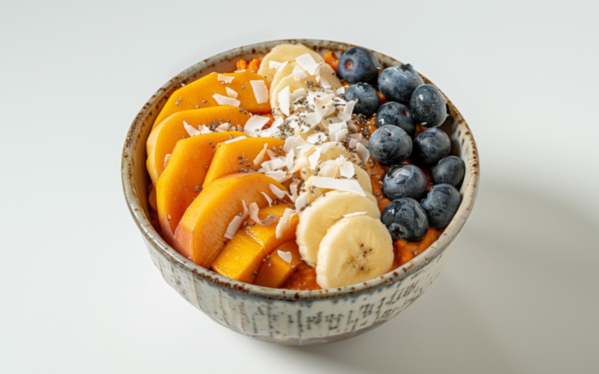 Eine Süßkartoffel-Bowl mit Banane, Pfirsich, Blaubeeren und Koksflocken.