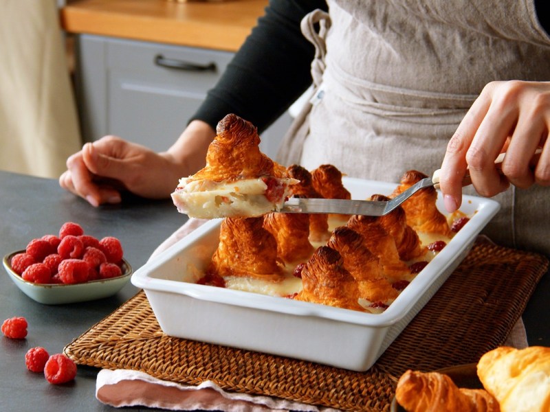 Ein Stück Croissant-Auflauf wird hochgehalten. Dahinter ist der restliche Auflauf zu sehen.