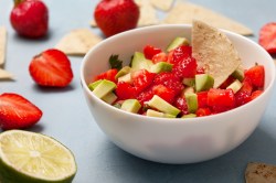 Erdbeer-Avocado-Salsa in einer weißen Schüssel. Dazu wird ein Tortilla-Chip serviert