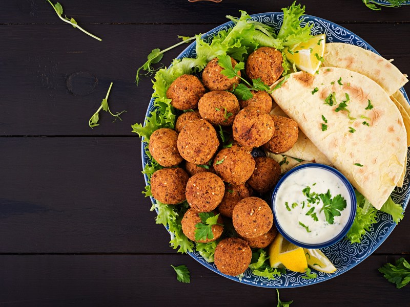 Falafel selber machen: Falafelbällchen auf einem Teller. Dazu Salat, Fladenbrot und Joghurtdip