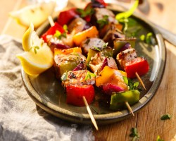 Drei Lachs-Kebab-Spieße vom Grill auf einem Teller