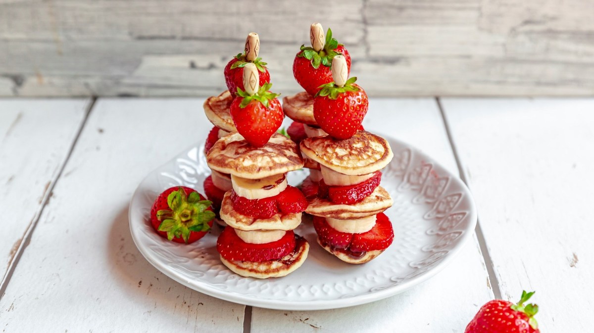 4 Pancake-Kebab-Spieße mit Bananen und Erdbeeren auf einem Teller