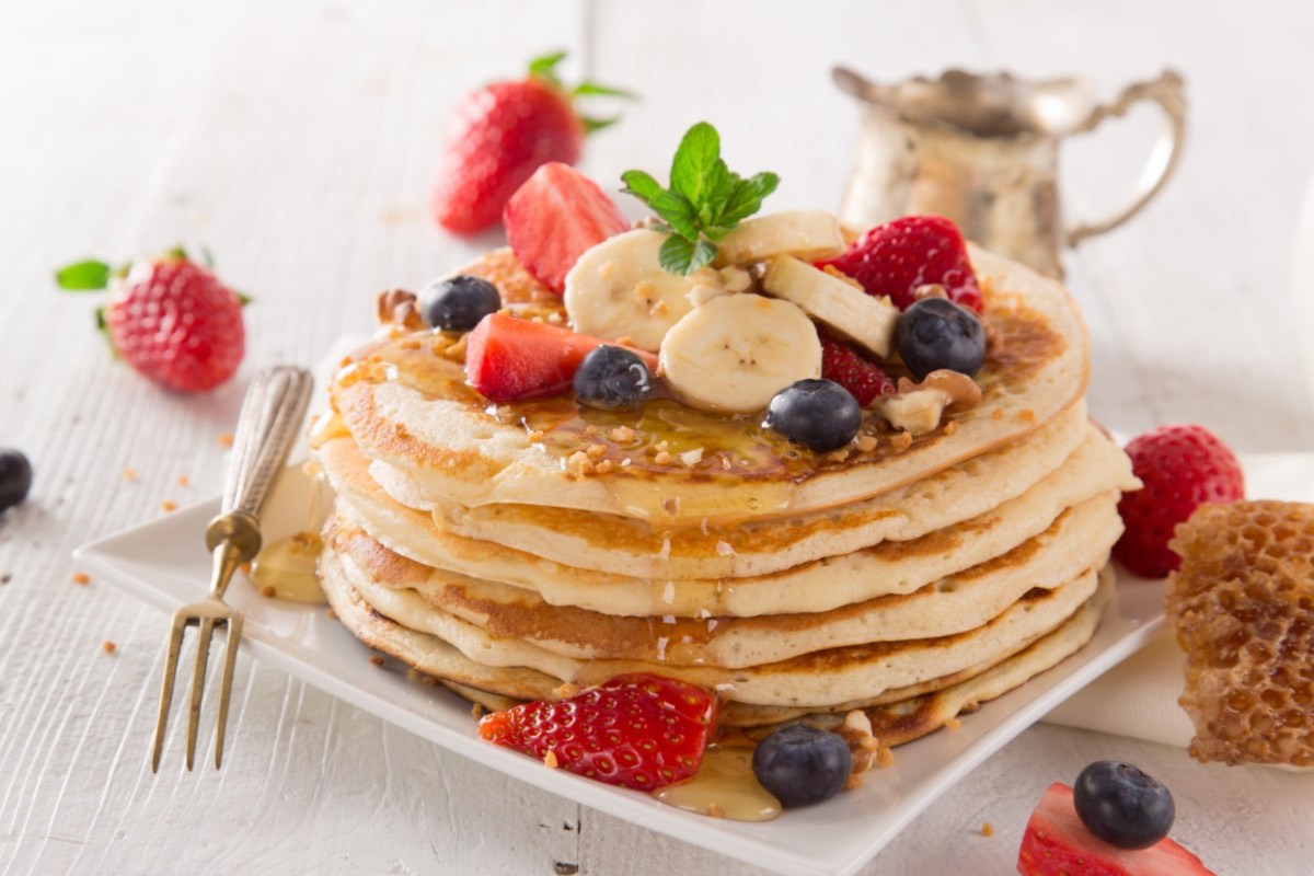 Ein Stapel Pancakes ohne Ei, mit Beeren, Nüssen und Ahornsirup.