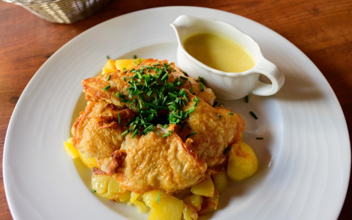 Pannfisch mit Bratkartoffeln und Senfsoße auf einem weißen Teller.