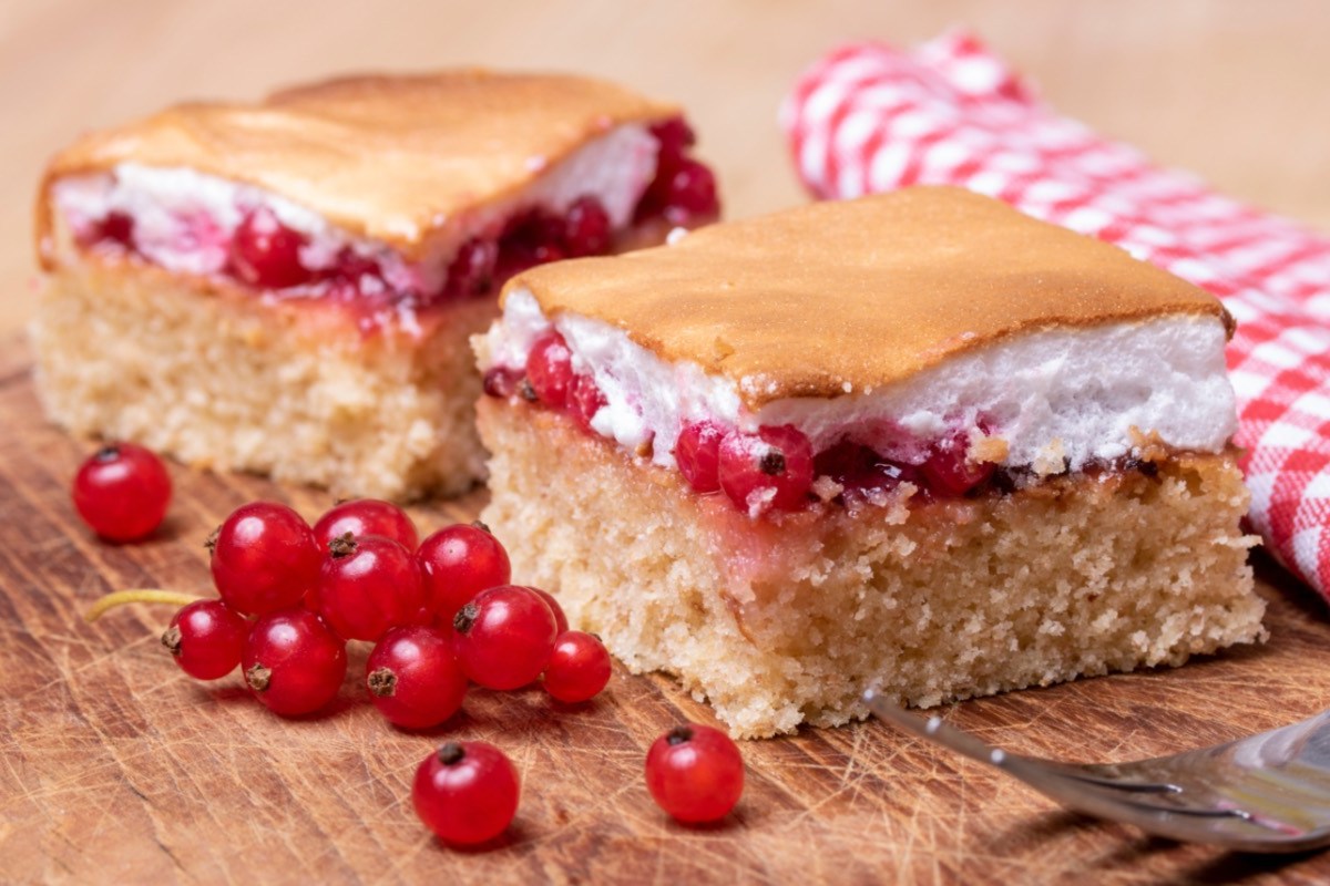 Zwei Stücke Ribiselkuchen. Daneben frische Johannisbeeren.