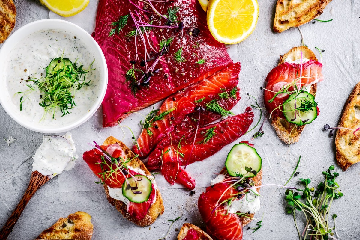 Tisch mit gebeiztem Lachs mit Roter Bete, Zitrone, Brot und Aufstrich