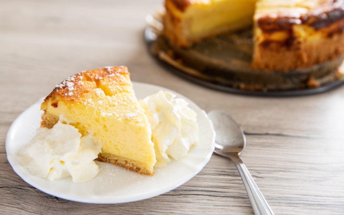 Tipps für Käsekuchen: Ein Stück Quarkkuchen mit Sahne auf einem Teller.