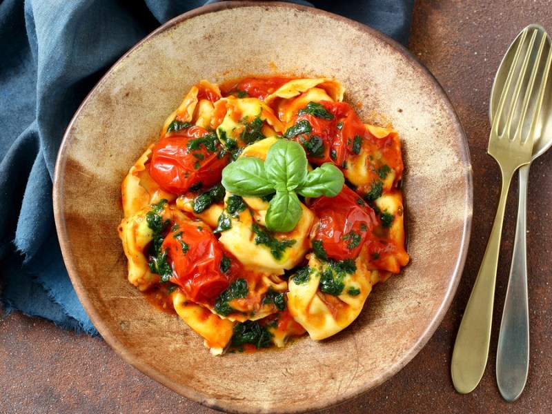 Tortellini al Forno auf einem braunen Teller mit Besteck