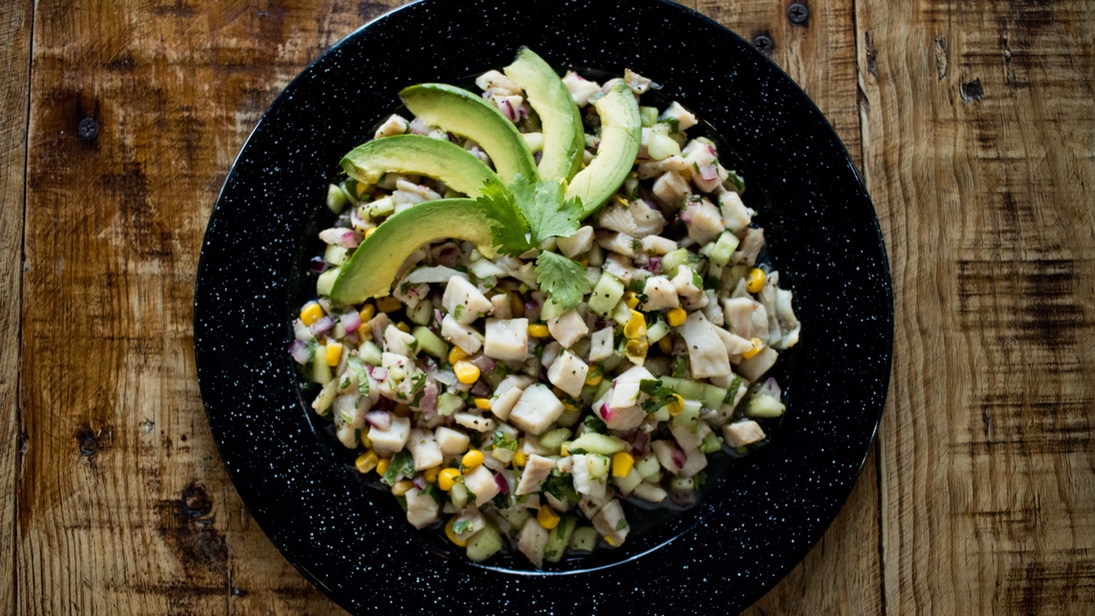 Veganes Ceviche auf schwarzem Teller und braunen Tisch.