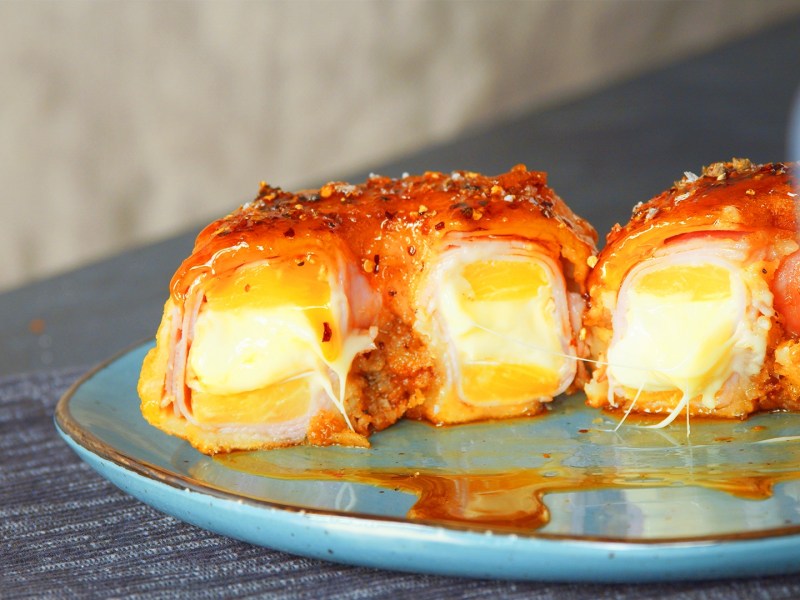 ein halbierter Ananas-Schinken-Krapfen mit Käse auf einem Teller.