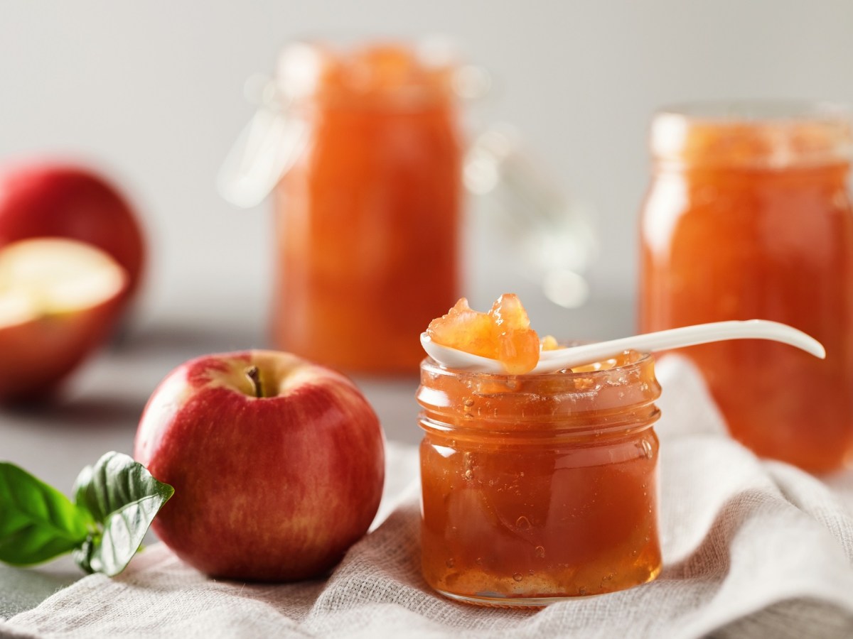 Ein SchÃ¤lchen mit Apfel-Salzkaramell-Marmelade. Dahinter liegen frische Ã„pfel.