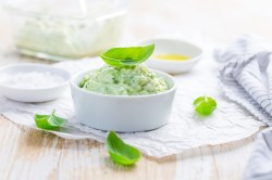 Avocado-Aufstrich mit Frischkäse in einer weißen Schale, garniert mit Basilikum.