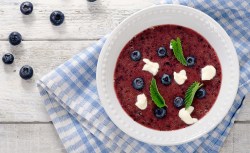 Teller mit schwedischer Blaubeersuppe und blau-weiß-kariertem Tischtuch