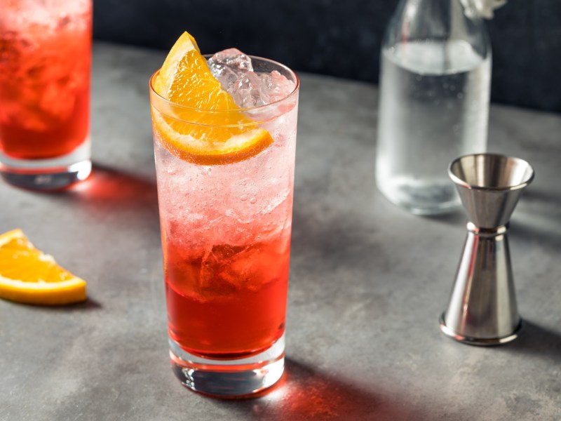 Campari Spritz in einem Glas mit Eiswürfeln. Dekoriert mit einer Scheibe Orange.