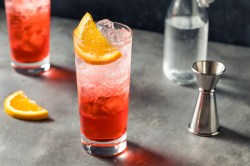 Campari Spritz in einem Glas mit Eiswürfeln. Dekoriert mit einer Scheibe Orange.