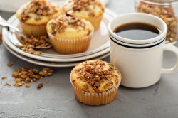 Cappuccino-Muffins auf einem Teller, einer steht davor, daneben eine Tasse Kaffee.