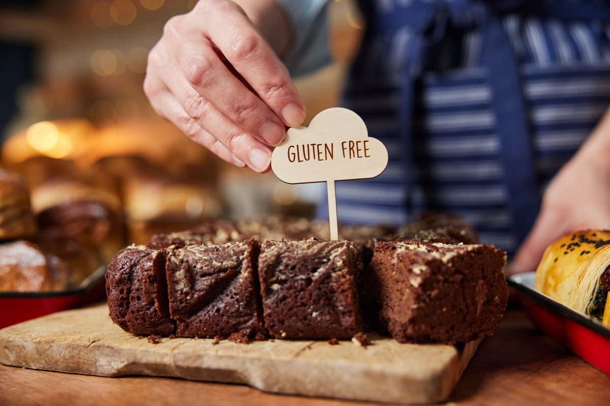 Glutenfreie Kuchen: Eine Hand steckt ein Label mit der Aufschrift "gluten free" in einen Schokokuchen.