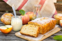 Ein Joghurtkuchen mit Apfel auf einem Holzbrett.