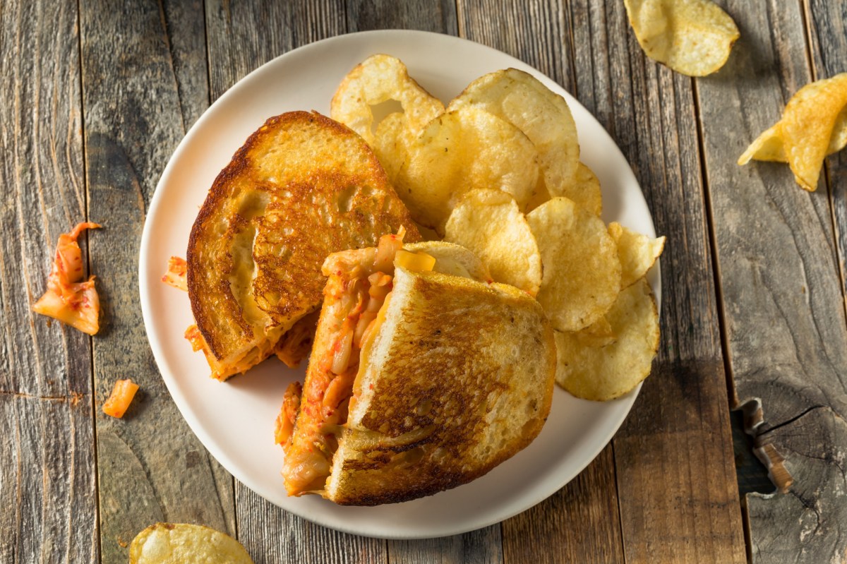 Kimchi Grilled Cheese auf einem hellen Teller, serviert mit Kartoffelchips.