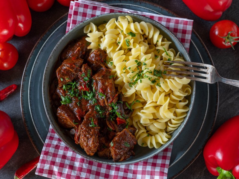 Ein Teller Nudeln mit Gulasch.