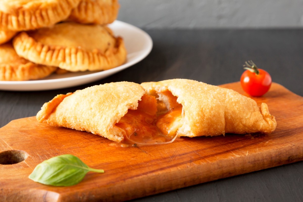 Ein Panzerotti mit Tomate-Mozzarella-Füllung, der in der Mitte durchgeschnitten wurde.