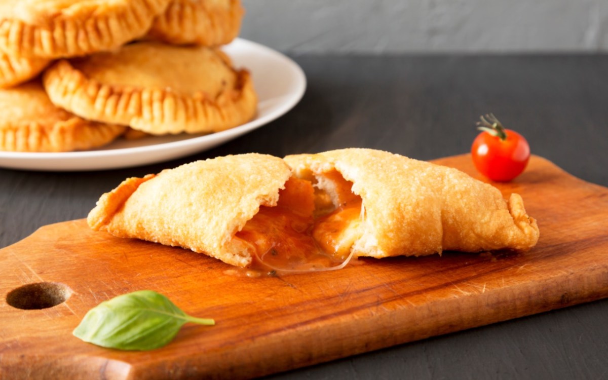 Ein Panzerotti mit Tomate-Mozzarella-Füllung, der in der Mitte durchgeschnitten wurde.