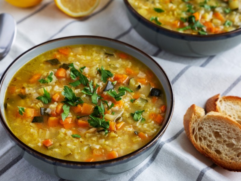 Eine Schüssel Reissuppe. Daneben liegen 2 Stücke Brot.